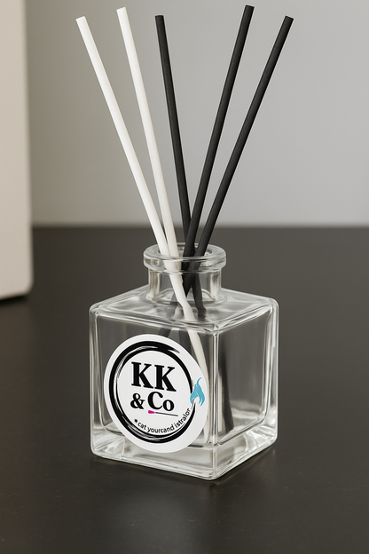Glass diffuser bottle with black and white sticks on a dark surface, featuring a KK & Co label.