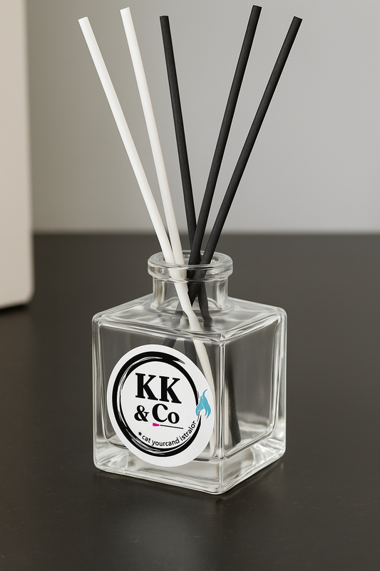 Glass diffuser bottle with black and white sticks on a dark surface, featuring a KK & Co label.