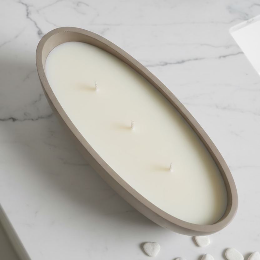 Oval-shaped candle in a beige holder on a marble surface